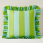 Striped pillow with ruffled edges in green and blue on a plain background