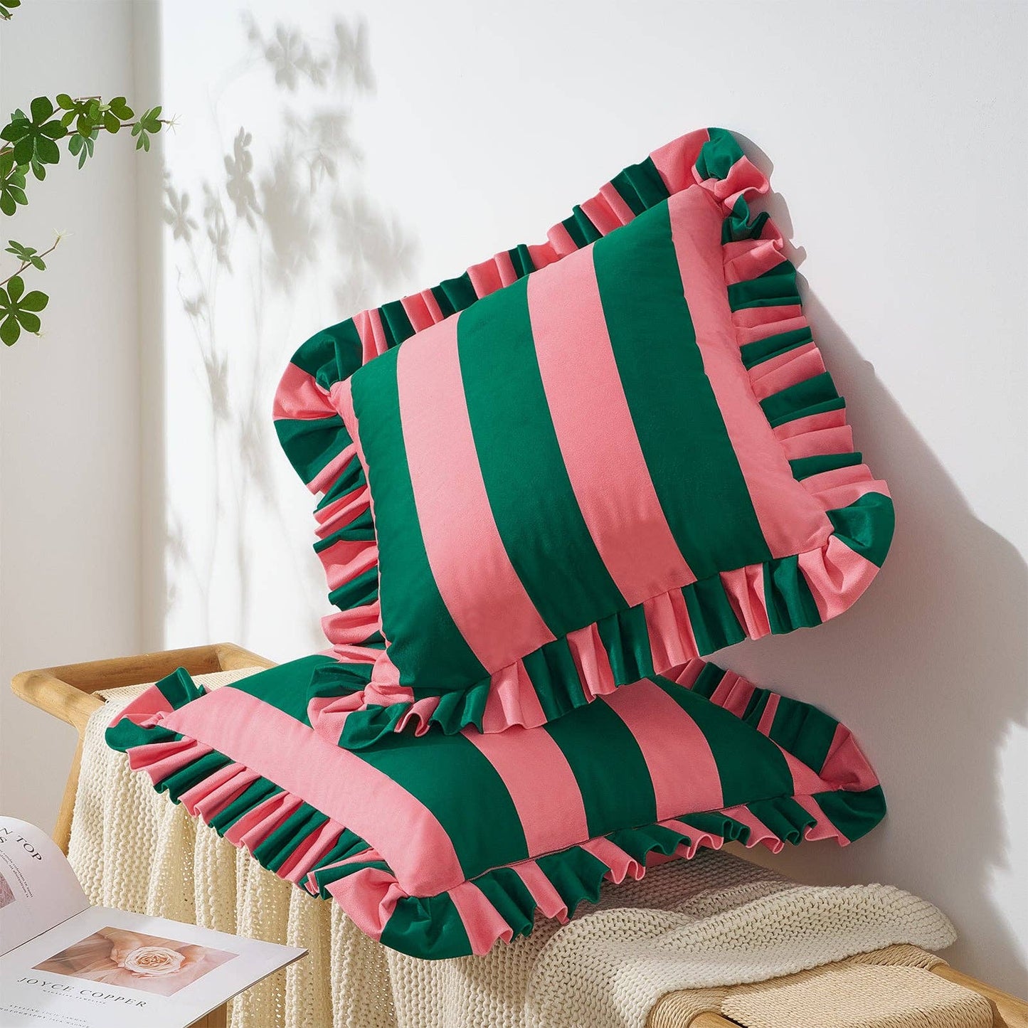 Striped pink and green pillow on a wooden chair with a white wall background