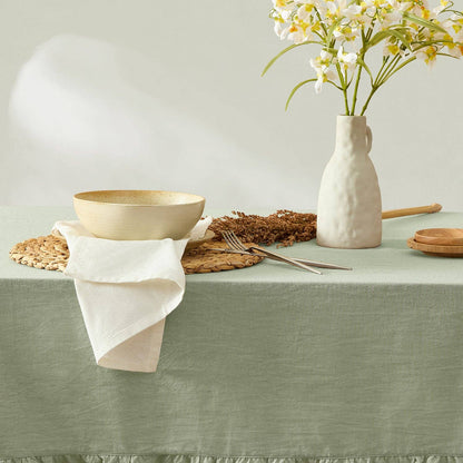Table setting with a bowl, vase, and cutlery on a green tablecloth.