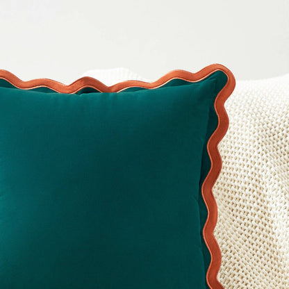 Teal pillow with brown scalloped edge on a white background