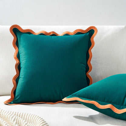 Teal pillows with wavy brown edges on a white couch