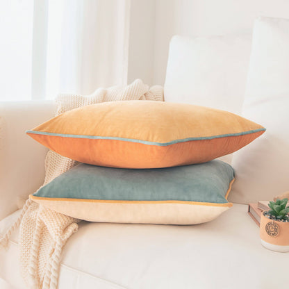 Two colorful pillows stacked on a couch with a neutral background