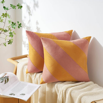 Two decorative pillows with pink and yellow diagonal stripes on a white couch.