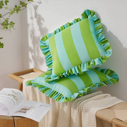 Green and blue striped pillows with ruffles on a wooden surface.