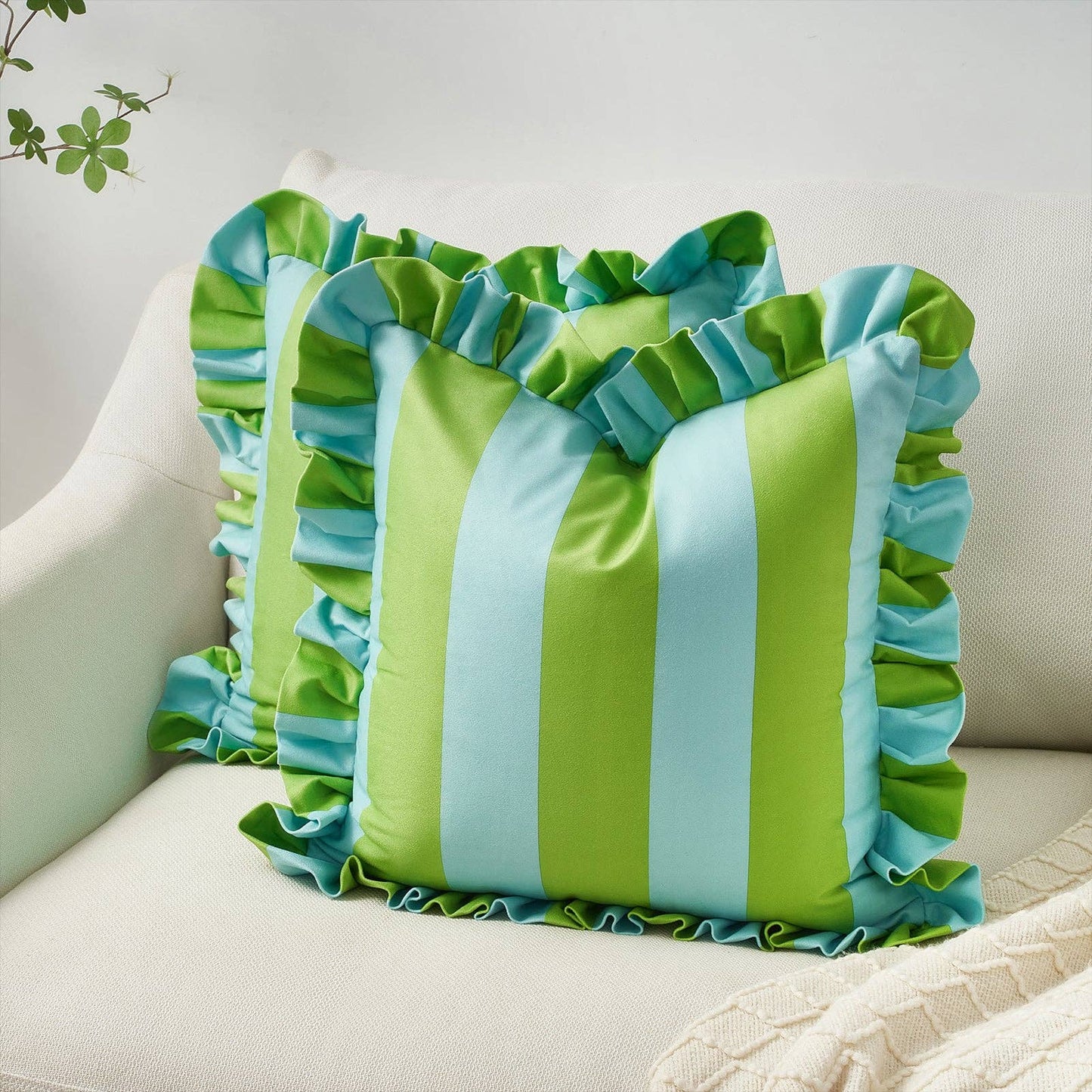 Green and blue striped pillow with ruffled edges on a beige couch.
