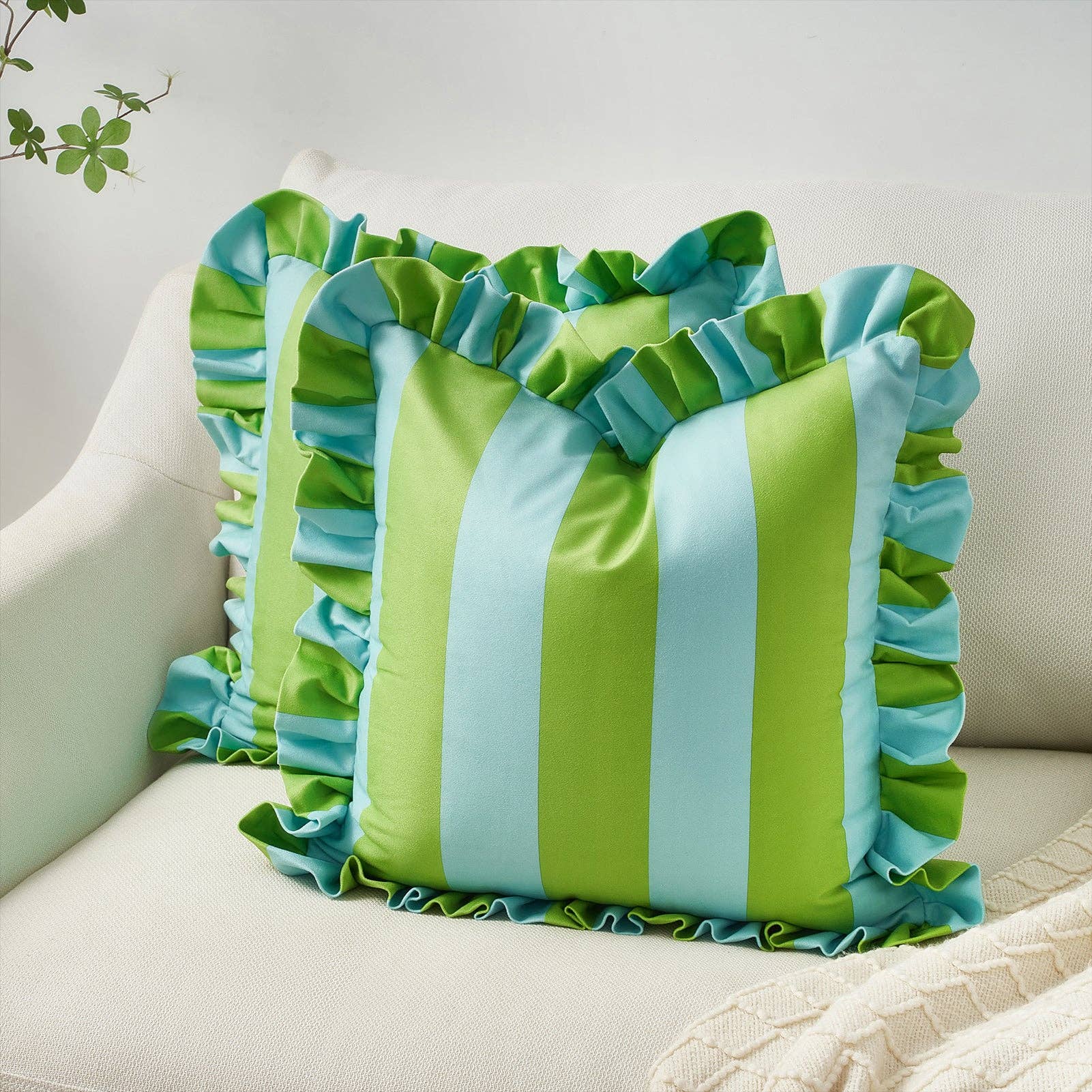 Green and blue striped pillow with ruffled edges on a beige couch.