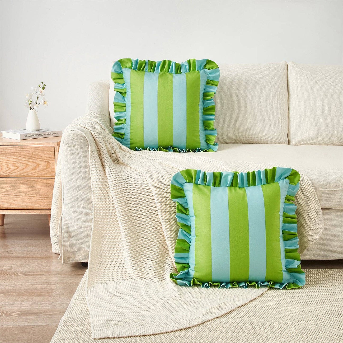 Green and blue striped pillows on a beige sofa with a wooden side table in the background.