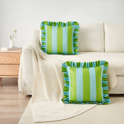 Green and blue striped pillows on a beige sofa with a wooden side table in the background.
