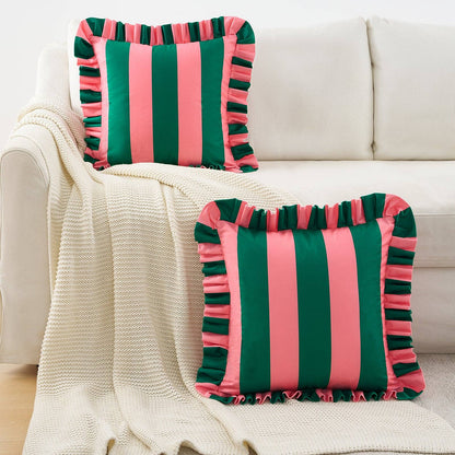 Two green and pink striped pillows with ruffles on a beige couch.