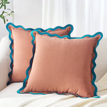 Two pink pillows with blue ruffled edges on a white couch.
