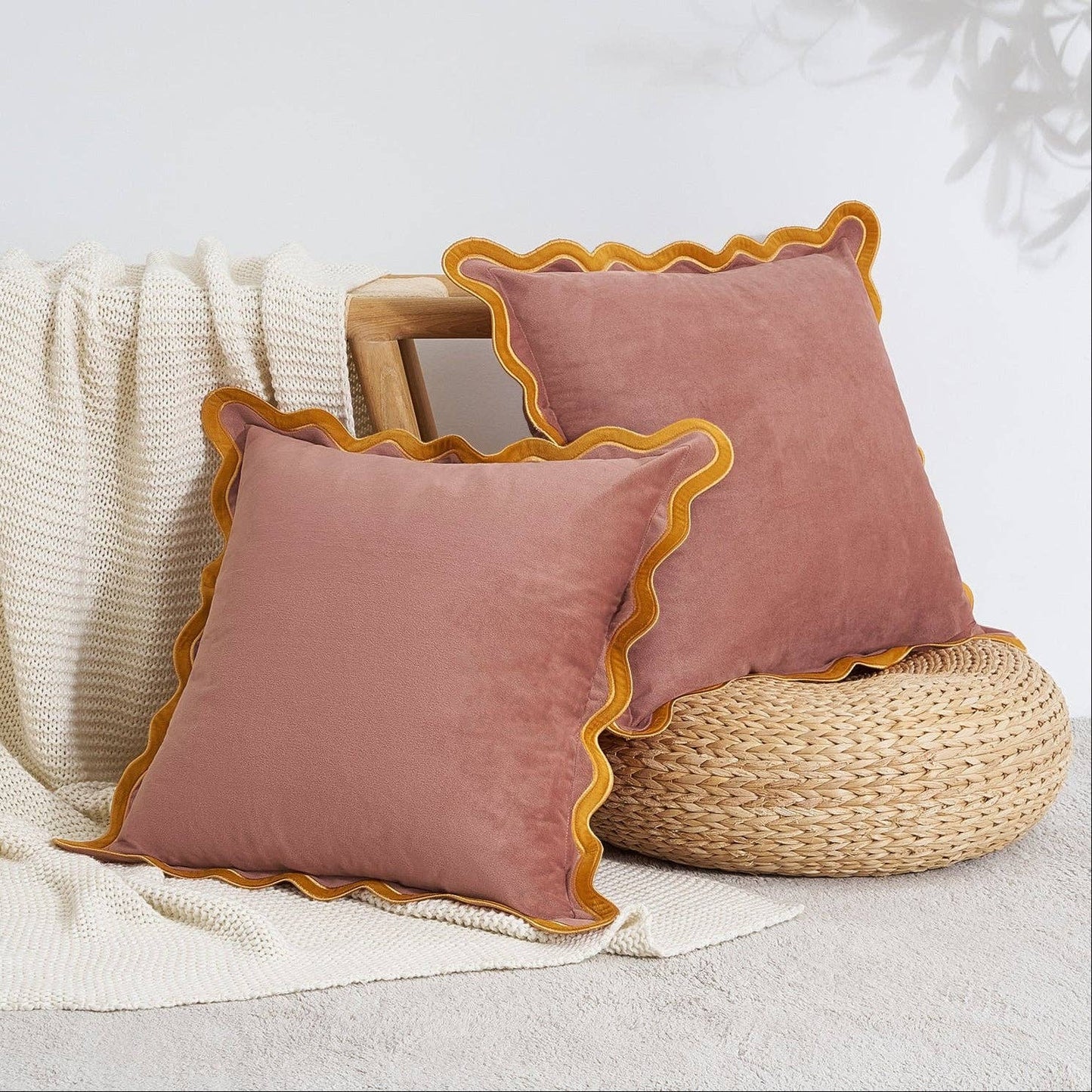 Two pink pillows with yellow trim on a textured surface.