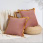 Two pink pillows with yellow trim on a textured surface.