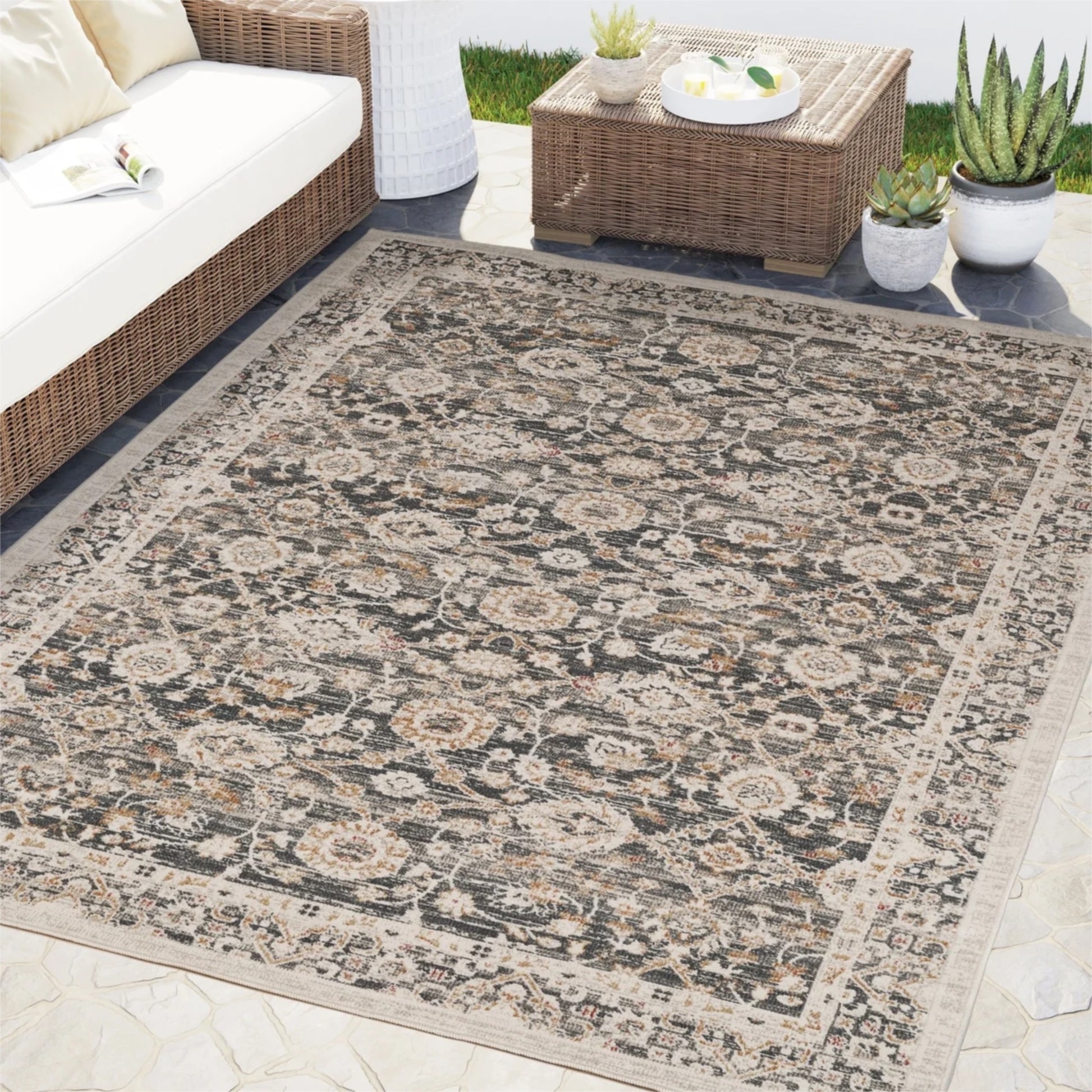 Patterned outdoor rug on a patio with furniture and plants.
