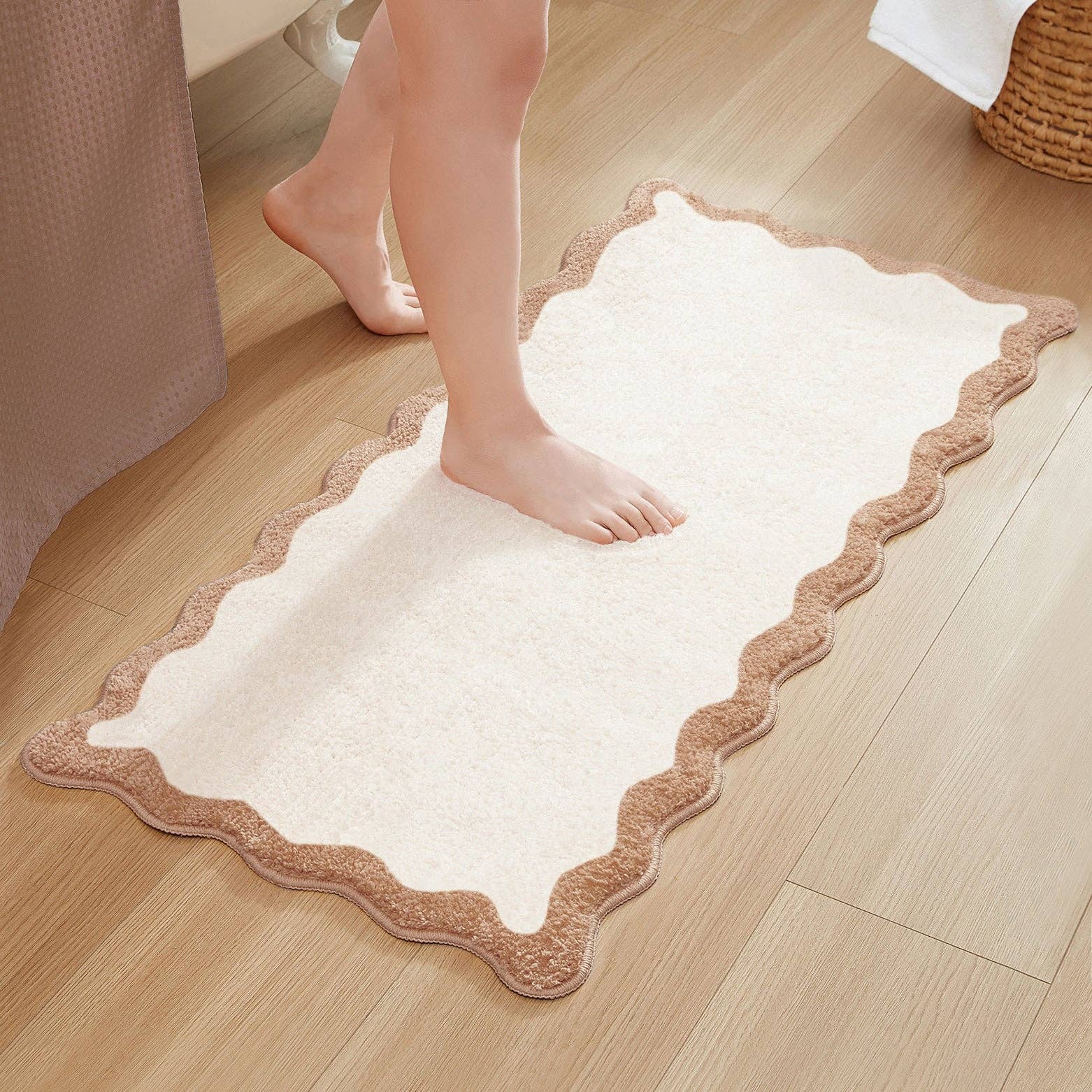 White bath mat with brown border on a wooden floor, person stepping onto it.