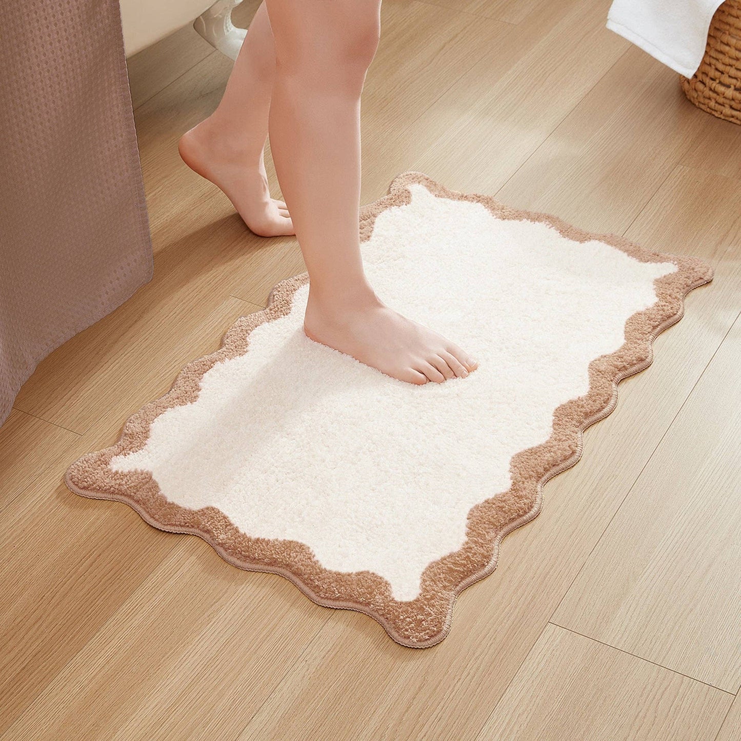 White bath mat with brown border on a wooden floor