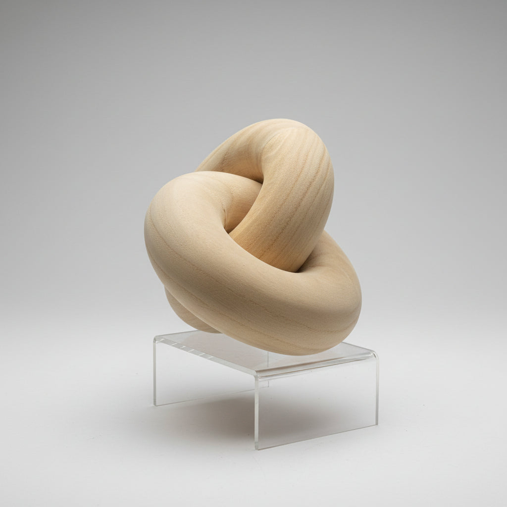 Wooden knot-shaped object on a gray surface with a white background