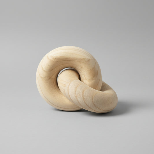 Wooden knot sculpture on a gray surface with a light-colored wall background