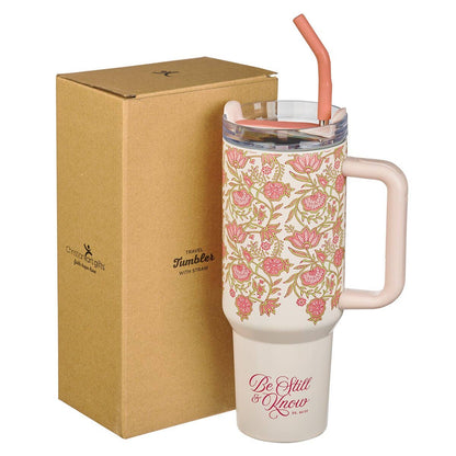 Floral-patterned tumbler with handle and straw next to a cardboard box on a white background