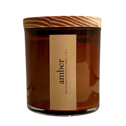 Amber-colored candle with a wooden lid and label on a white background
