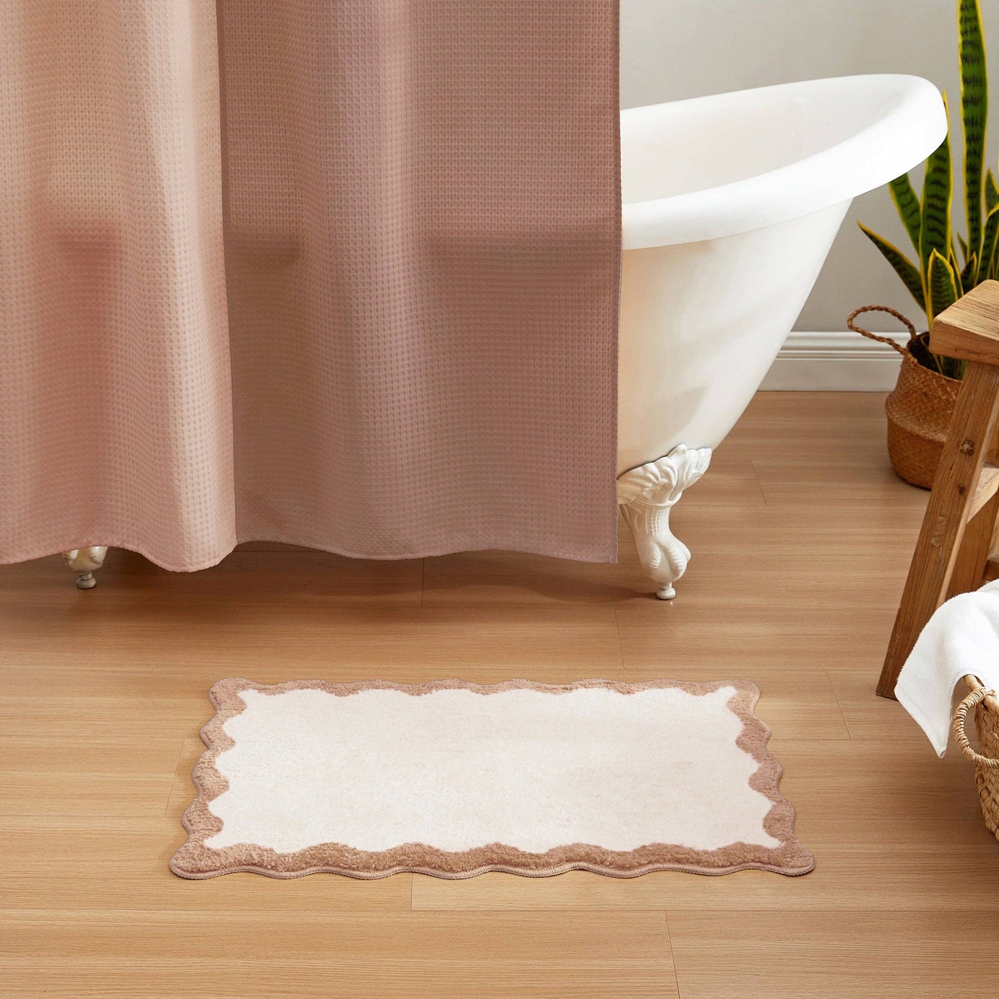 Bathroom with a bathtub, pink shower curtain, and white bath mat on wooden floor.