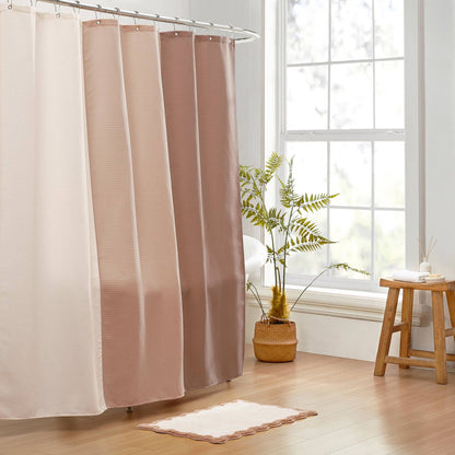 Shower curtain with a gradient design in a bathroom setting with a plant and stool.