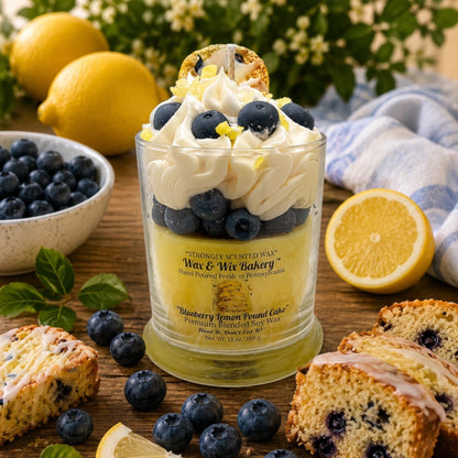 A glass jar candle from Wax & Wiz Bakery filled with layered blueberries, whipped cream, and lemon-yellow wax, styled on a wooden table with blueberries, lemons, scones, and a cloth in the background.