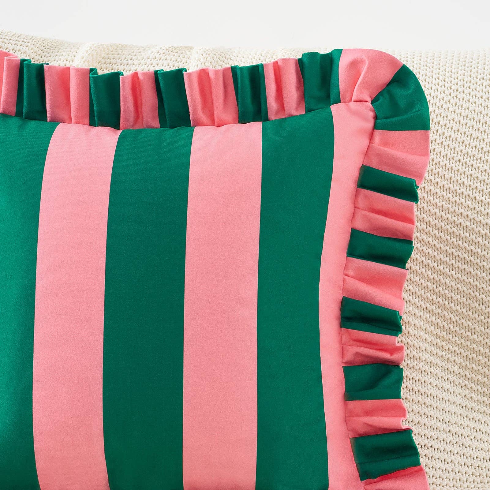 Striped pillow with green and pink horizontal stripes on a textured surface