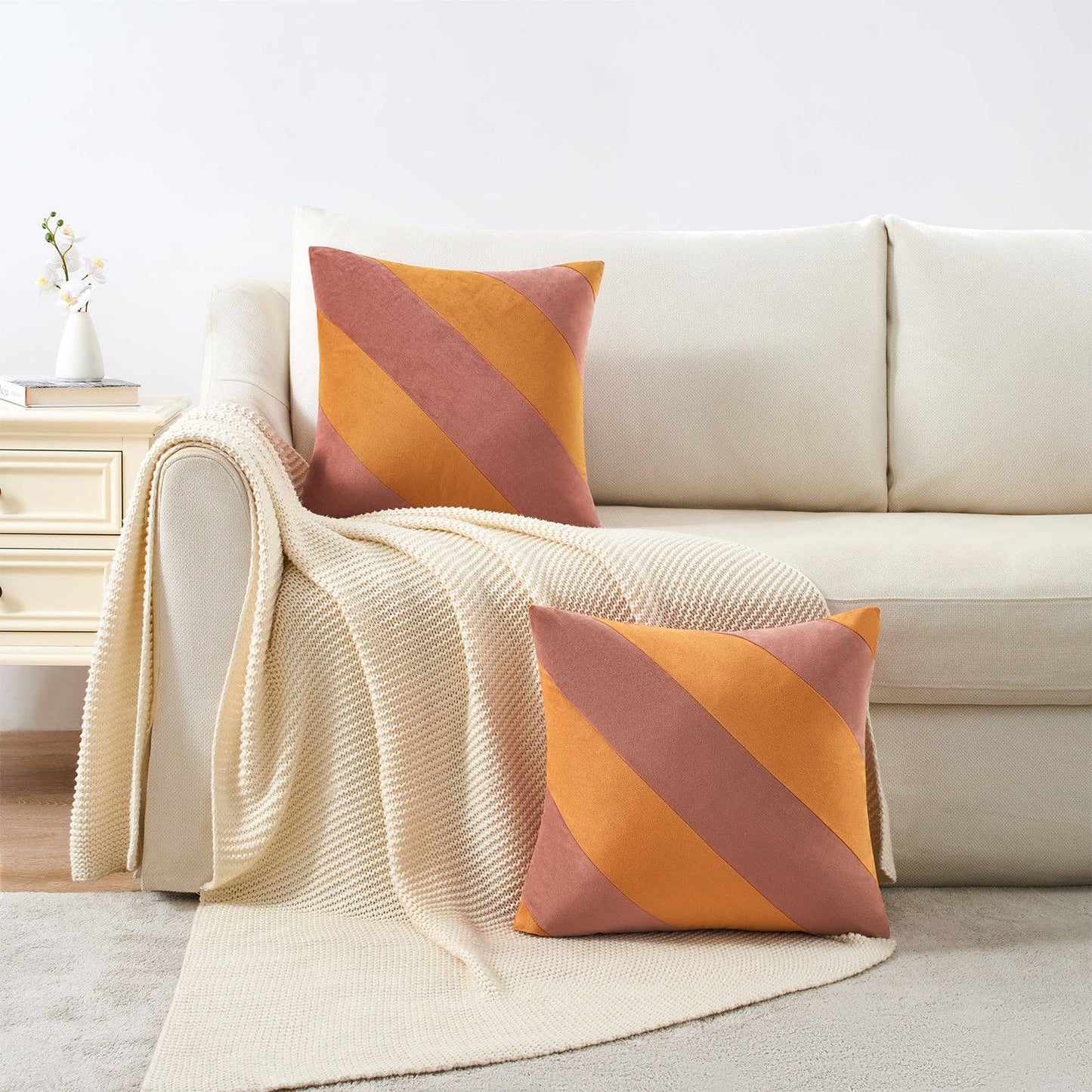 Beige sofa with striped orange and pink cushions and a matching throw blanket.