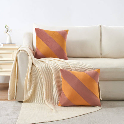 Beige sofa with striped orange and pink cushions and a matching throw blanket.