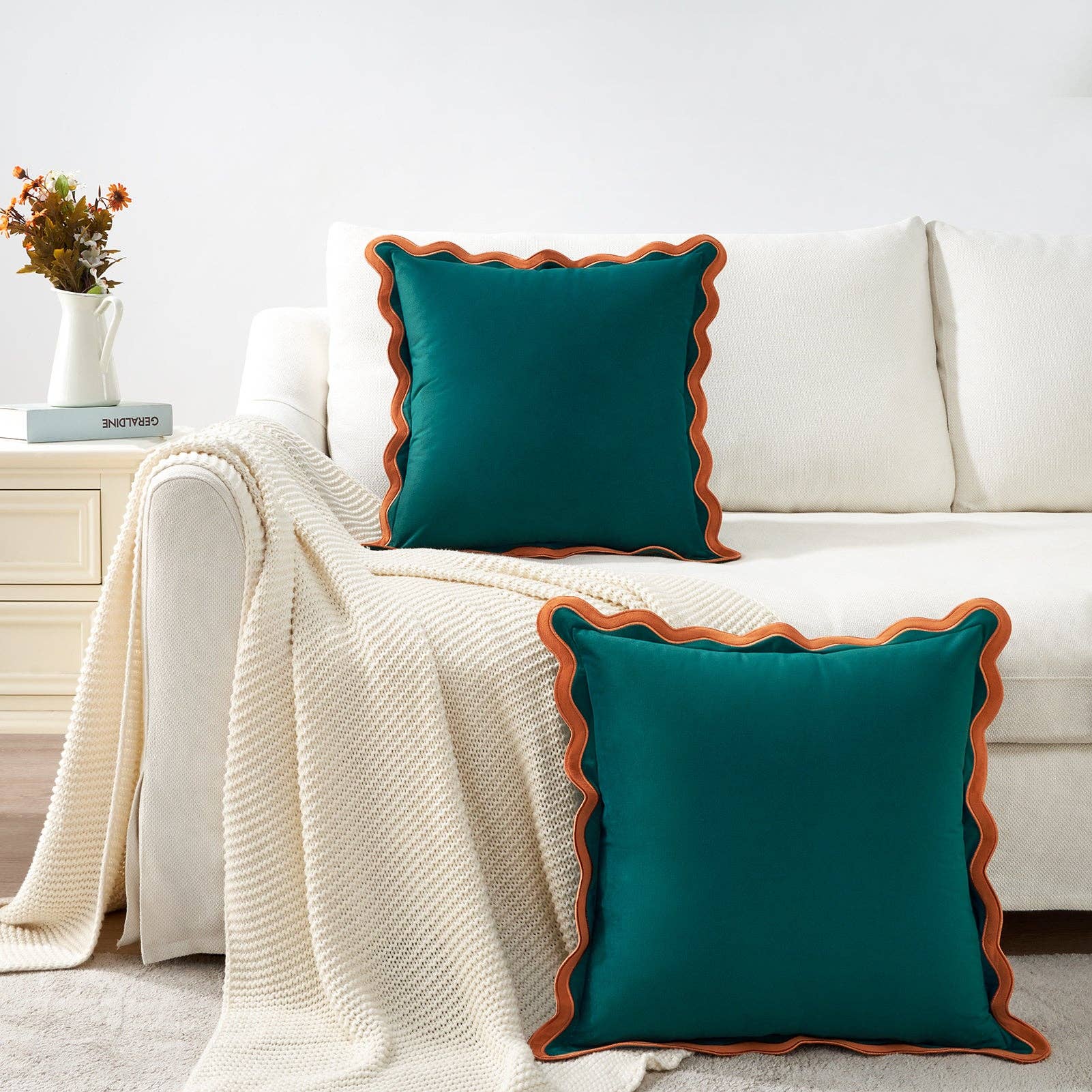Teal pillows with brown trim on a white sofa in a living room setting.