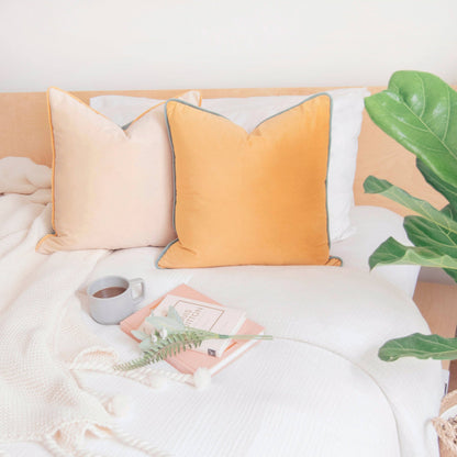 Cozy bedroom with a bed featuring yellow and beige pillows, a plant, and a cup.